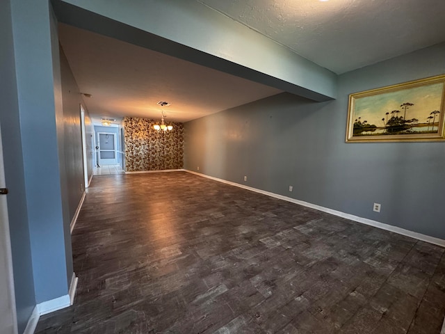 spare room with a chandelier and dark hardwood / wood-style floors