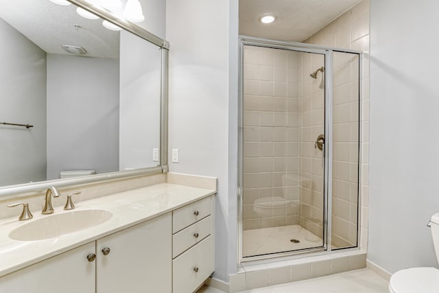 bathroom featuring a shower with door, vanity, a textured ceiling, and toilet