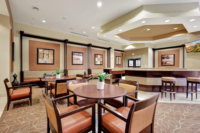 carpeted dining room featuring a barn door and a tray ceiling