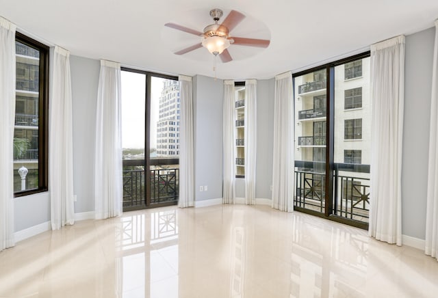 tiled empty room with ceiling fan and a wall of windows