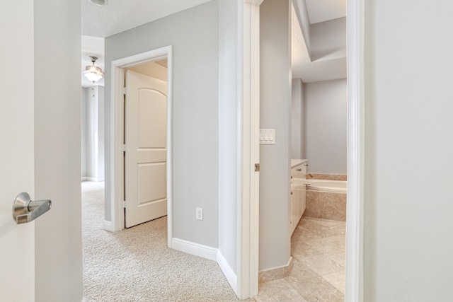 hallway with light carpet and a textured ceiling