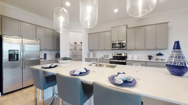 kitchen with stainless steel appliances, sink, crown molding, decorative light fixtures, and gray cabinets