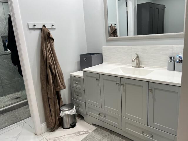 bathroom featuring walk in shower, tasteful backsplash, and vanity