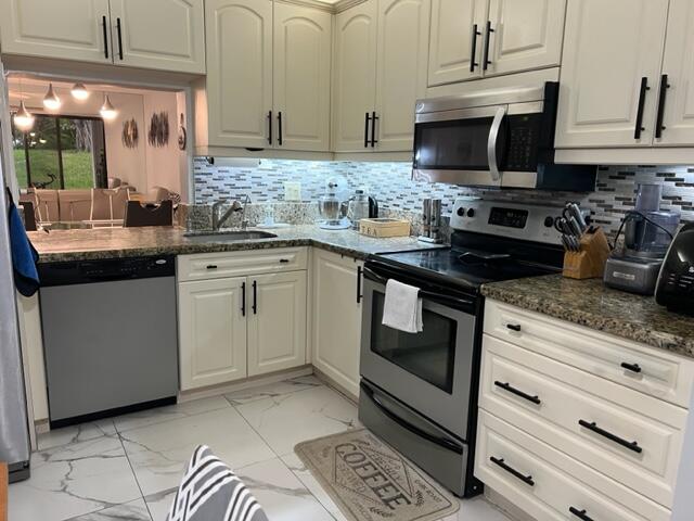 kitchen featuring tasteful backsplash, white cabinetry, appliances with stainless steel finishes, sink, and dark stone countertops