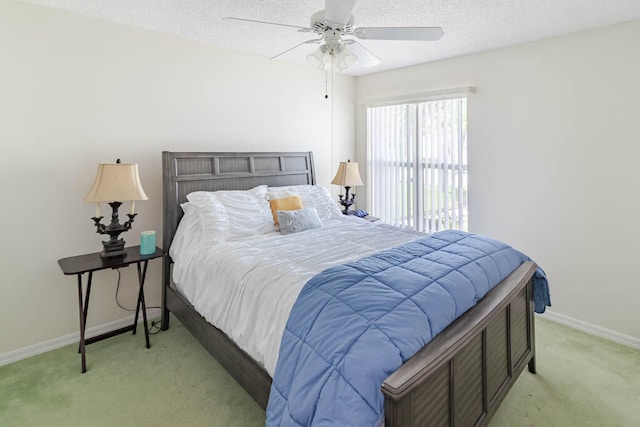 bedroom featuring ceiling fan, light colored carpet, and a textured ceiling