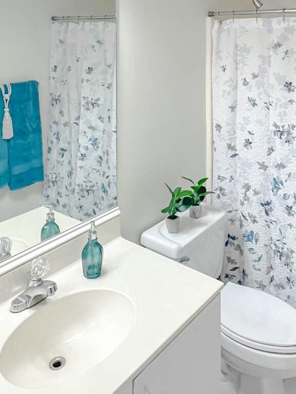 bathroom featuring a shower with curtain, vanity, and toilet