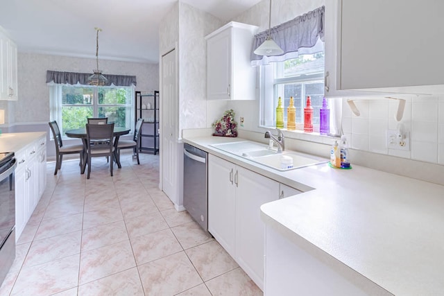 kitchen with stainless steel dishwasher, a wealth of natural light, sink, decorative light fixtures, and white cabinetry