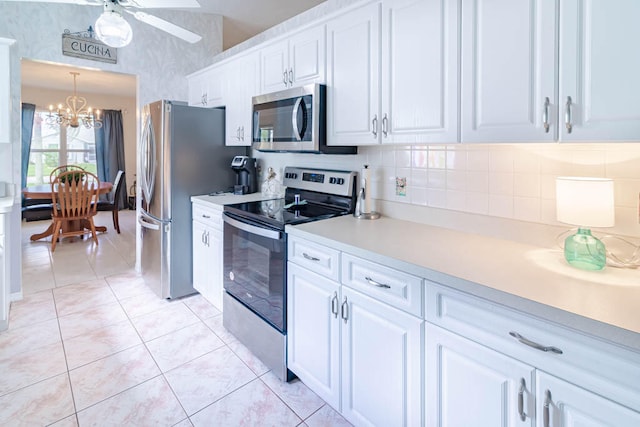 kitchen featuring white cabinetry, hanging light fixtures, stainless steel appliances, backsplash, and light tile patterned flooring