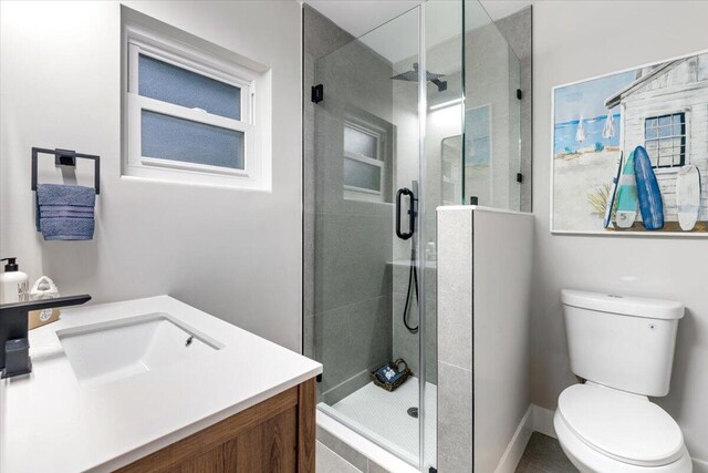 bathroom featuring a shower with door, vanity, and toilet