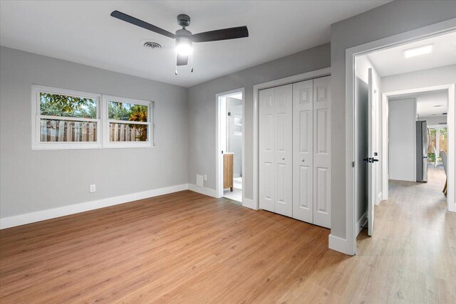 unfurnished bedroom featuring light hardwood / wood-style floors, multiple windows, a closet, and ceiling fan