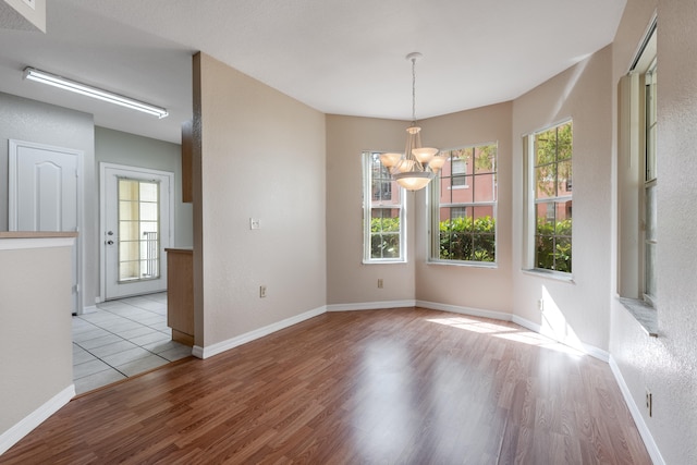 unfurnished dining area with light hardwood / wood-style flooring and a notable chandelier