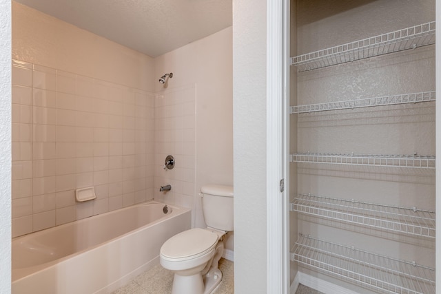 bathroom featuring toilet, tiled shower / bath, a textured ceiling, and tile patterned floors