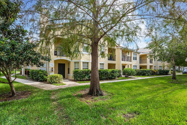 view of front of house with a balcony and a front lawn