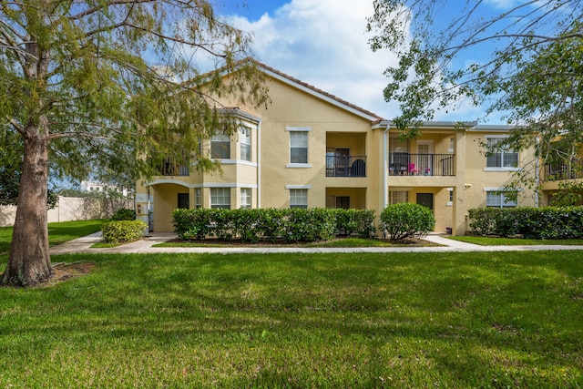 view of front of house with a balcony and a front lawn