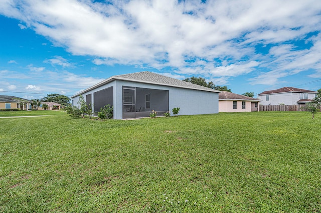 rear view of house with a sunroom and a lawn