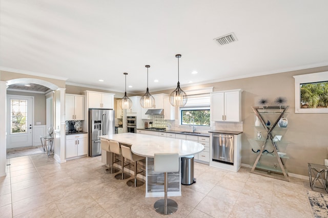 kitchen with a kitchen island, decorative light fixtures, a kitchen bar, white cabinets, and appliances with stainless steel finishes