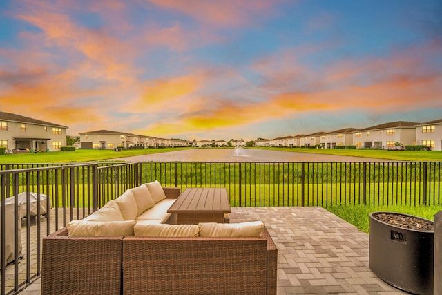 patio terrace at dusk featuring a yard, a residential view, fence, and an outdoor hangout area