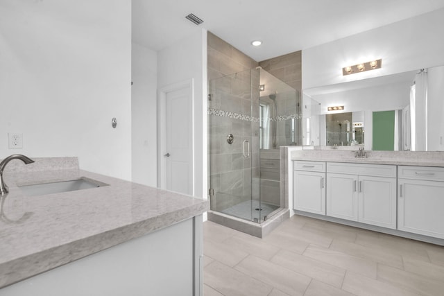 full bath with two vanities, a stall shower, visible vents, and a sink