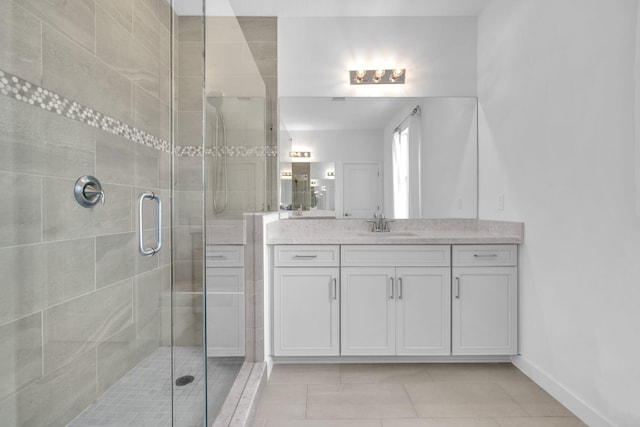 full bathroom featuring tile patterned flooring, baseboards, a shower stall, and vanity