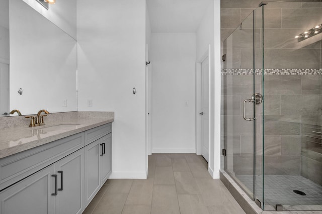 full bath featuring a stall shower, tile patterned flooring, baseboards, and vanity