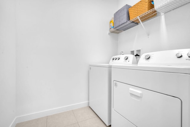 laundry area featuring laundry area, light tile patterned flooring, baseboards, and washing machine and clothes dryer