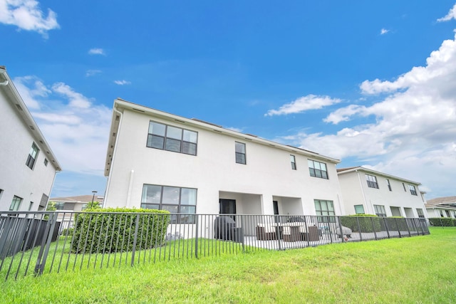 back of property featuring a yard, fence, and stucco siding