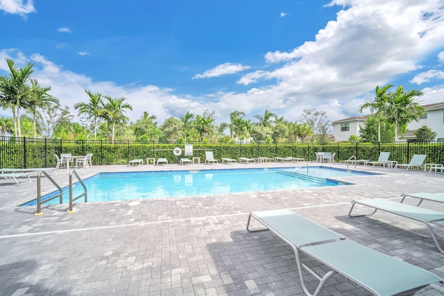 pool with a patio area and fence