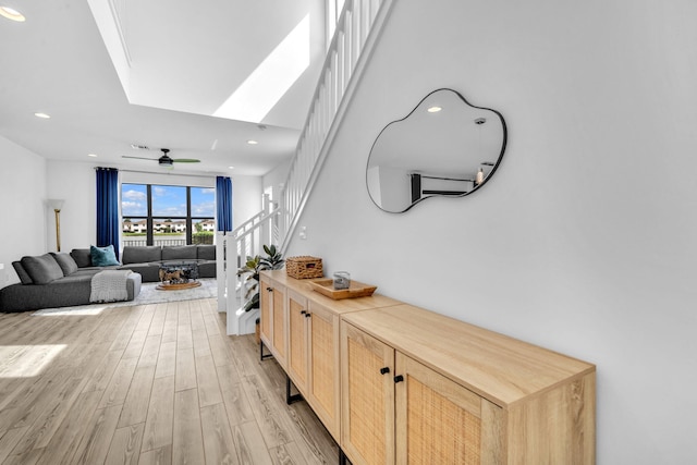 hall with light wood finished floors, stairs, and recessed lighting