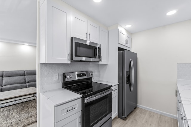 kitchen featuring stainless steel appliances, white cabinetry, light stone countertops, light hardwood / wood-style flooring, and decorative backsplash