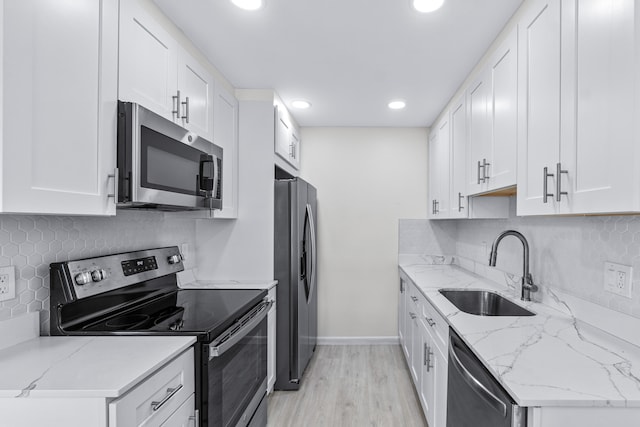 kitchen featuring light stone counters, light hardwood / wood-style flooring, sink, white cabinetry, and appliances with stainless steel finishes