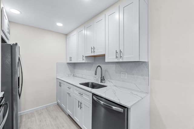 kitchen with stainless steel appliances, light hardwood / wood-style floors, white cabinetry, sink, and light stone counters