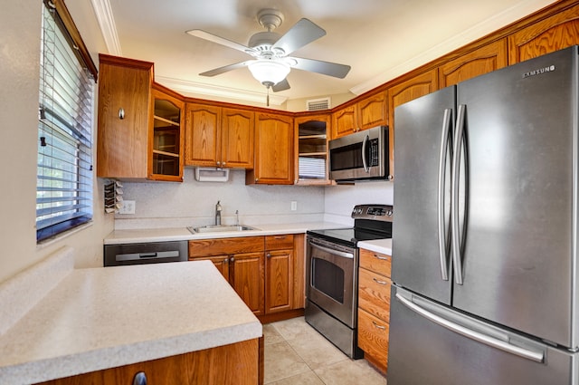 kitchen with ceiling fan, appliances with stainless steel finishes, ornamental molding, light tile patterned flooring, and sink