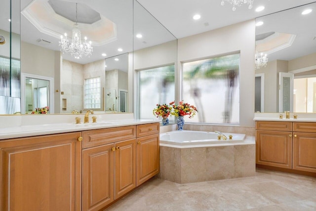 bathroom featuring a healthy amount of sunlight, a tray ceiling, and a notable chandelier