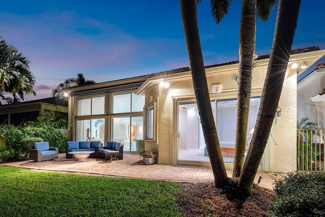 back house at dusk featuring an outdoor living space and a patio area