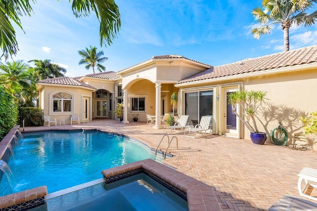back of house featuring an in ground hot tub, a tiled roof, stucco siding, a patio area, and an outdoor pool