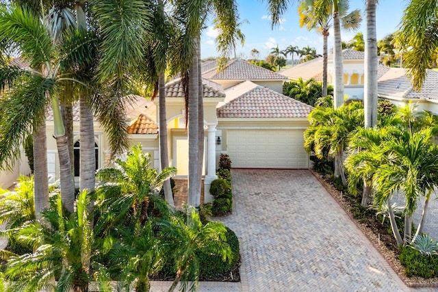 23 Island Dr, Boynton Beach, FL 33436 - view of side of home featuring a tile roof, an attached garage, stucco siding, and driveway