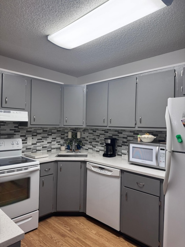 kitchen with white appliances, gray cabinetry, and sink