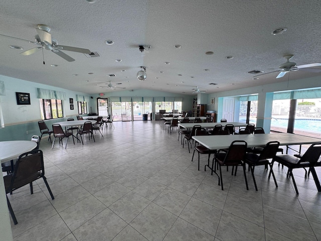 tiled dining area with ceiling fan, vaulted ceiling, and a textured ceiling