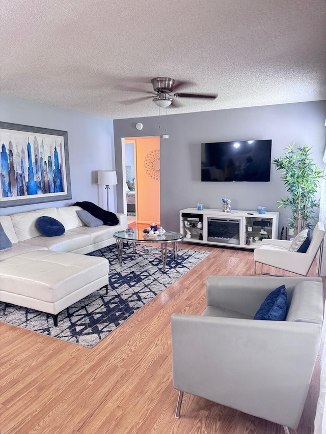 living room featuring a textured ceiling, hardwood / wood-style floors, and ceiling fan