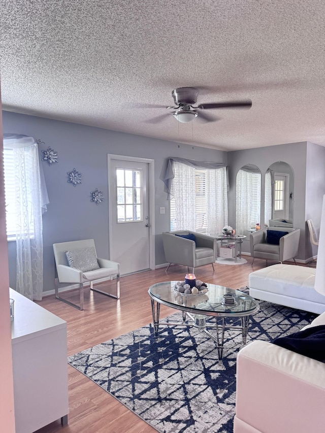 living room with ceiling fan, a textured ceiling, and hardwood / wood-style flooring