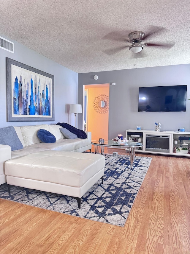 living room featuring a textured ceiling, ceiling fan, and hardwood / wood-style flooring