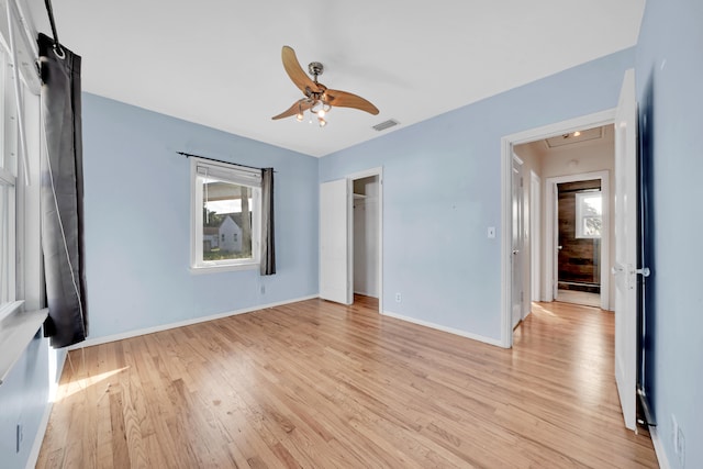 unfurnished bedroom featuring light hardwood / wood-style flooring, a closet, a walk in closet, and ceiling fan