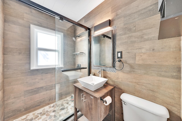 bathroom with vanity, wooden walls, toilet, and walk in shower