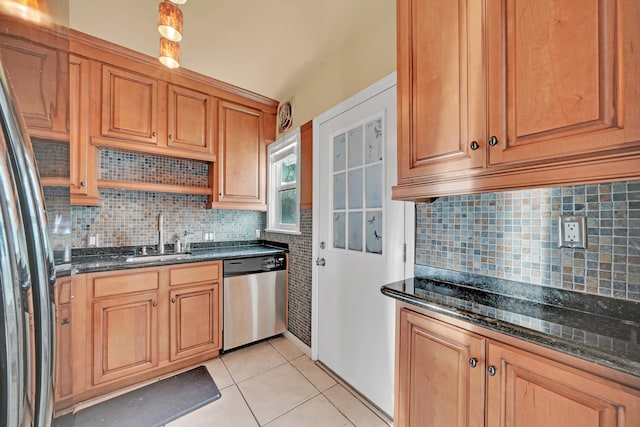 kitchen featuring appliances with stainless steel finishes, sink, dark stone counters, and light tile patterned floors