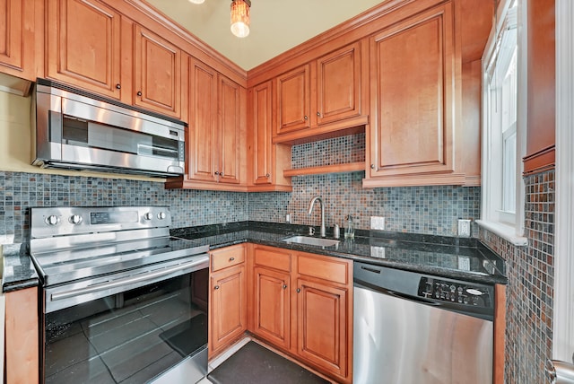 kitchen with sink, dark stone countertops, stainless steel appliances, and tasteful backsplash