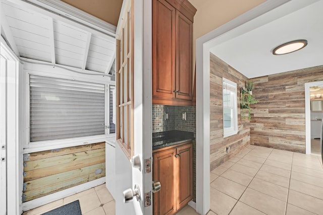 kitchen featuring tasteful backsplash, light tile patterned floors, and wooden walls