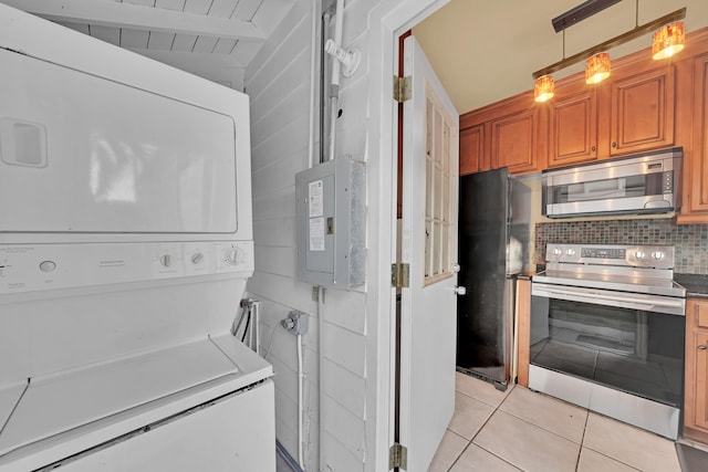 kitchen with stacked washer and clothes dryer, decorative light fixtures, light tile patterned floors, electric panel, and appliances with stainless steel finishes