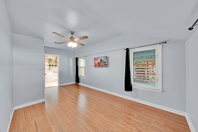 spare room with vaulted ceiling, light wood-type flooring, a healthy amount of sunlight, and ceiling fan