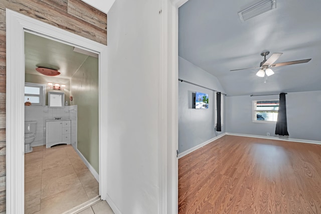 hallway with vaulted ceiling and light wood-type flooring