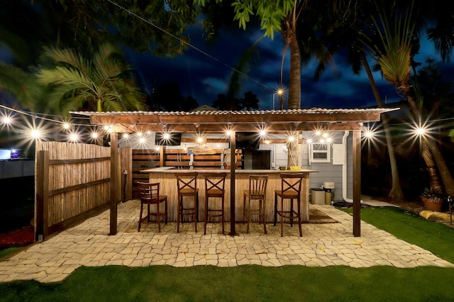 patio at night featuring exterior bar